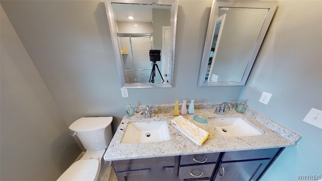 full bath with a sink, a shower stall, toilet, and double vanity