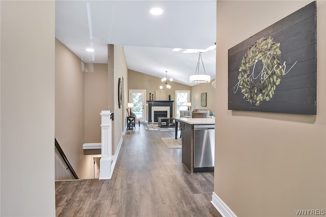 hallway featuring dark hardwood / wood-style floors, lofted ceiling, and a notable chandelier