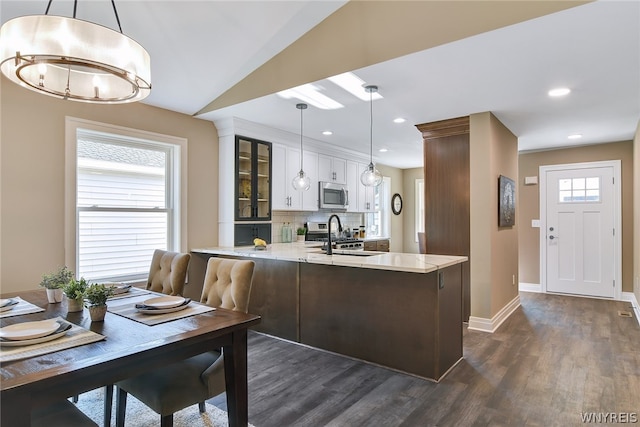 kitchen with kitchen peninsula, a wealth of natural light, decorative light fixtures, and appliances with stainless steel finishes