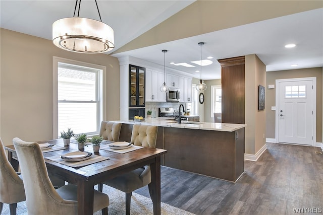 dining room with dark hardwood / wood-style flooring, lofted ceiling, and sink