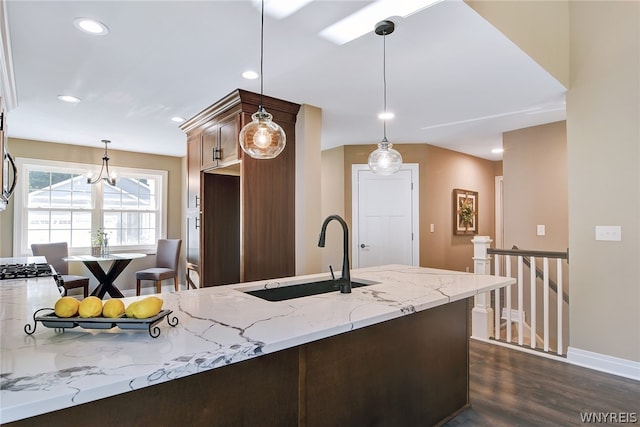 kitchen featuring dark hardwood / wood-style floors, light stone counters, hanging light fixtures, and sink