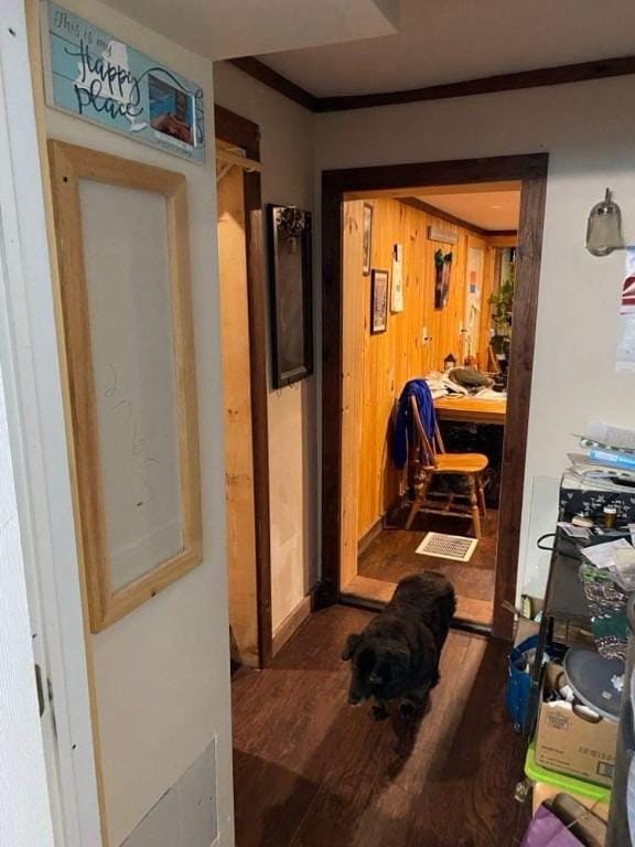 hall featuring ornamental molding, dark wood-type flooring, and wooden walls