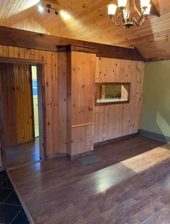 spare room with a chandelier, vaulted ceiling, wooden ceiling, and wood walls