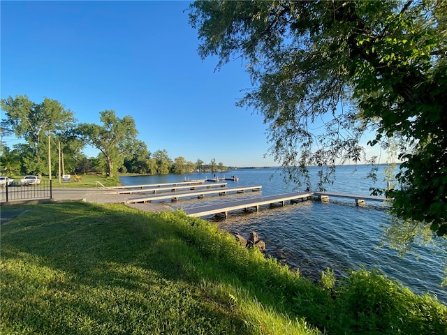 view of dock with a lawn and a water view