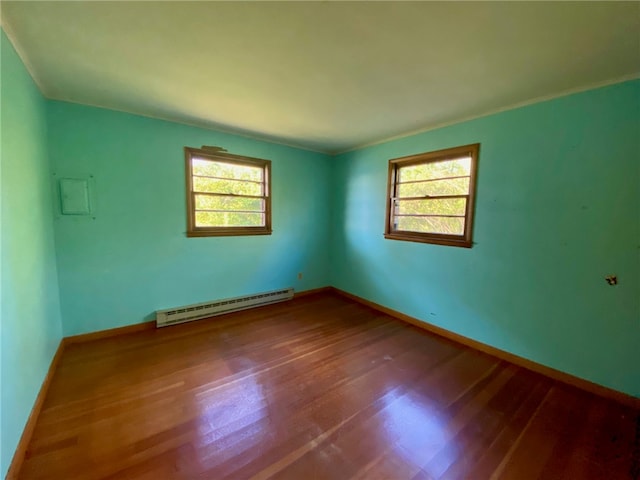 unfurnished room with hardwood / wood-style flooring, baseboard heating, and a healthy amount of sunlight