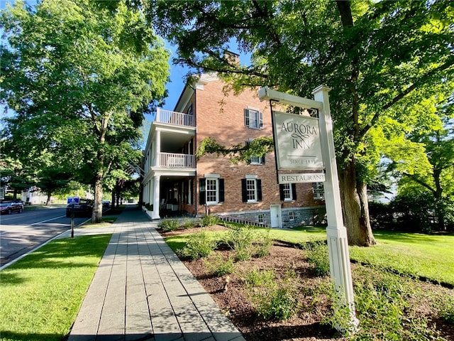 view of front facade with a front yard and a balcony