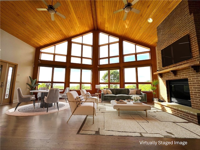 living room featuring hardwood / wood-style floors, ceiling fan, a high ceiling, and a brick fireplace