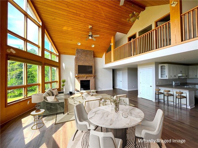 dining room featuring a brick fireplace, dark hardwood / wood-style flooring, high vaulted ceiling, and wooden ceiling