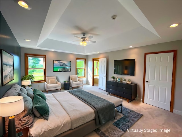 bedroom with ceiling fan, light colored carpet, and a tray ceiling