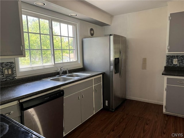 kitchen with gray cabinets, appliances with stainless steel finishes, sink, decorative backsplash, and dark wood-type flooring