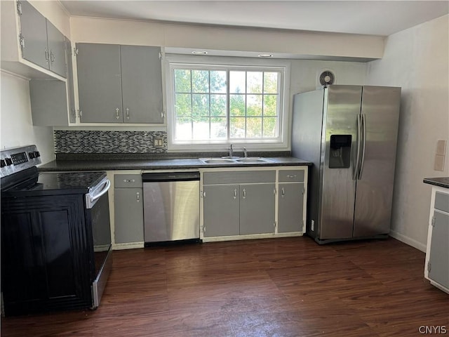 kitchen featuring appliances with stainless steel finishes, dark hardwood / wood-style flooring, sink, and gray cabinetry