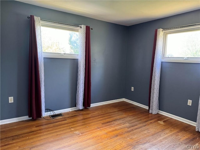 unfurnished room with hardwood / wood-style flooring and plenty of natural light