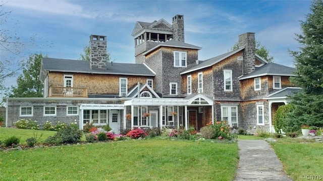 rear view of property featuring a balcony and a lawn