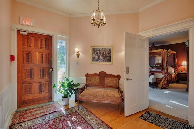 foyer entrance with an inviting chandelier, crown molding, and light hardwood / wood-style floors