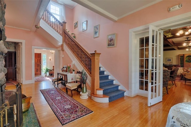 staircase featuring crown molding, coffered ceiling, wood-type flooring, french doors, and beamed ceiling