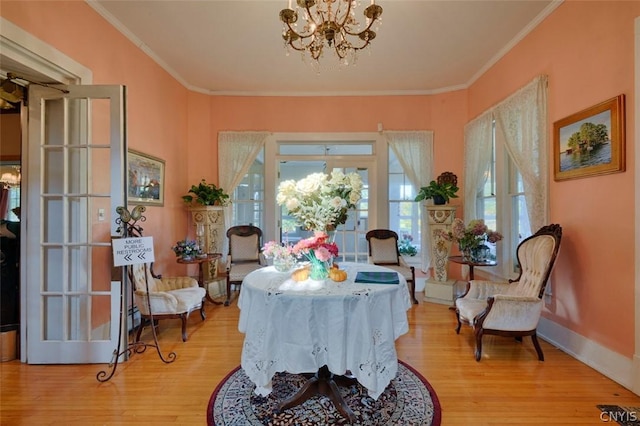 living area with an inviting chandelier, crown molding, and light wood-type flooring