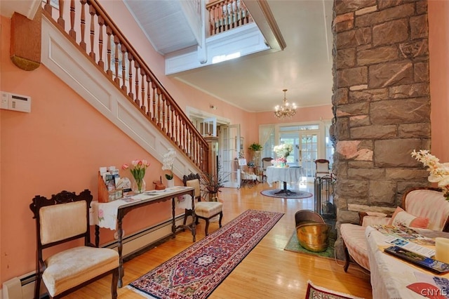 entryway with hardwood / wood-style flooring, a baseboard heating unit, and an inviting chandelier