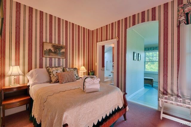 bedroom featuring ensuite bathroom and dark colored carpet