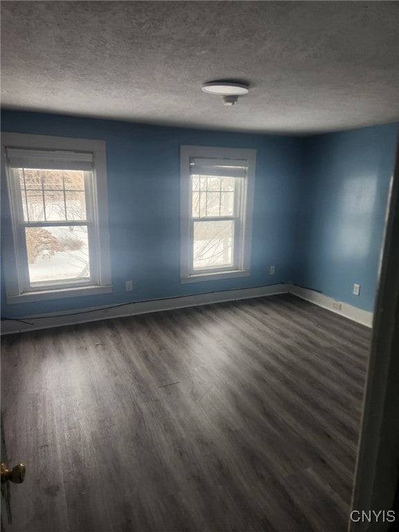 spare room with a textured ceiling and dark hardwood / wood-style floors