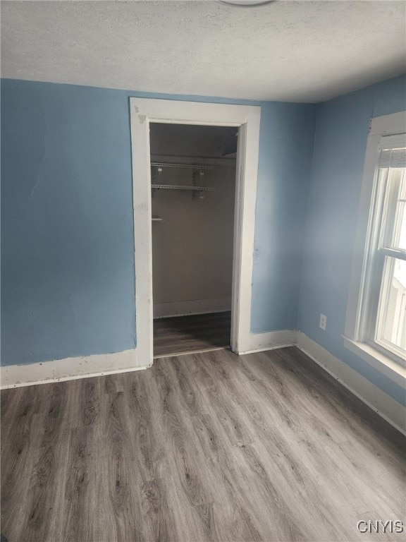 unfurnished bedroom with wood-type flooring, a closet, and a textured ceiling