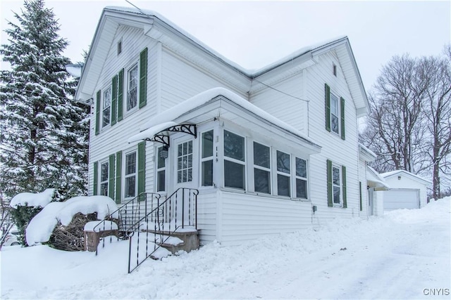 snow covered property featuring an outbuilding and a garage