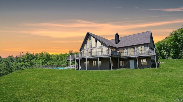 back house at dusk with a yard and a deck