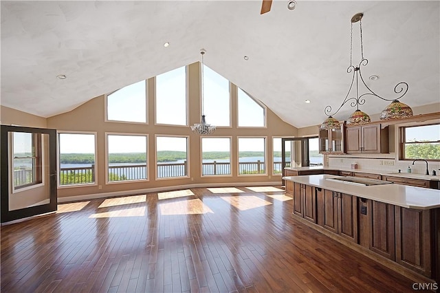 kitchen with wood-type flooring, a water view, high vaulted ceiling, a chandelier, and a kitchen island