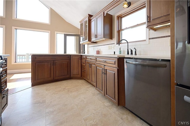 kitchen featuring backsplash, light tile patterned floors, stainless steel appliances, and vaulted ceiling