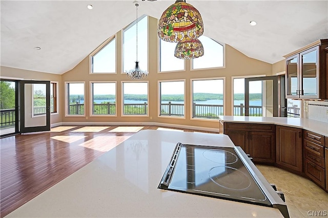 kitchen featuring plenty of natural light, a water view, a notable chandelier, and light wood-type flooring