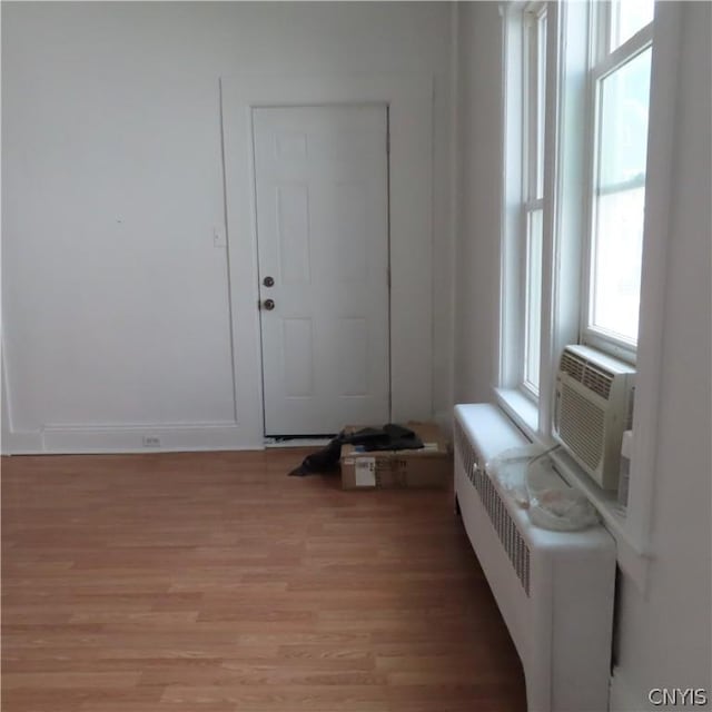 entryway featuring cooling unit, radiator heating unit, and light hardwood / wood-style flooring