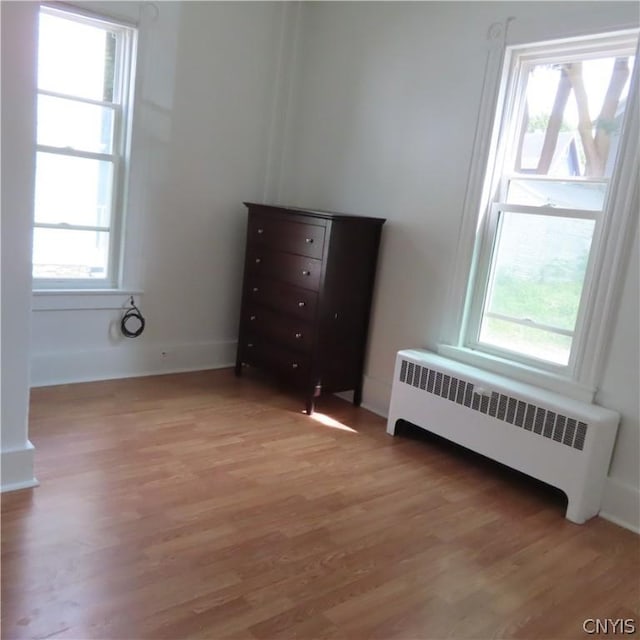 unfurnished bedroom with radiator heating unit, light hardwood / wood-style flooring, and multiple windows