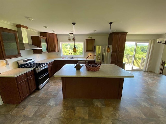 kitchen with sink, a kitchen island, stainless steel appliances, and wall chimney range hood