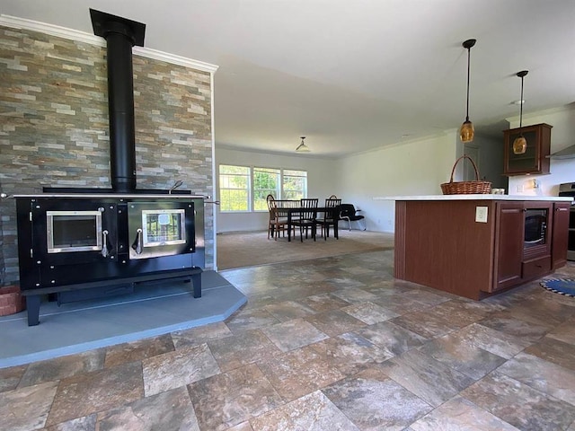 kitchen featuring dark brown cabinetry, stainless steel appliances, crown molding, a wood stove, and hanging light fixtures