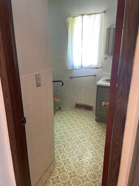 bathroom featuring tile flooring, tile walls, and vanity