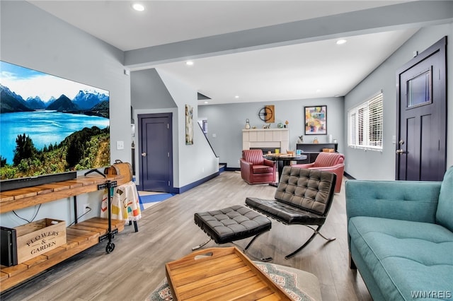 living room with beam ceiling, a tiled fireplace, and hardwood / wood-style floors