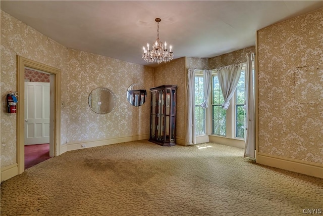 spare room featuring carpet flooring, a notable chandelier, and wallpapered walls