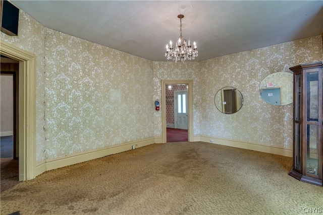 carpeted spare room featuring a chandelier and wallpapered walls