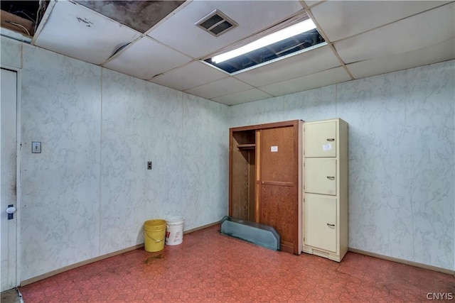 unfurnished room with tile patterned floors, visible vents, a drop ceiling, and baseboards