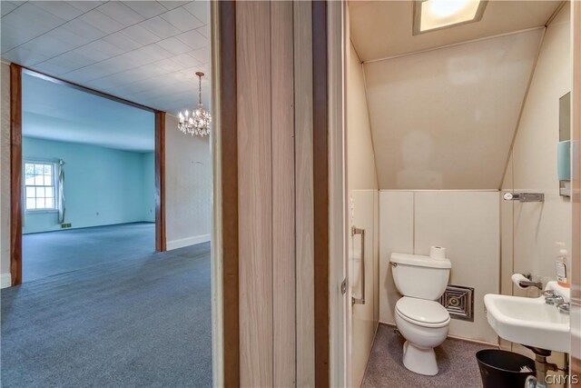 bathroom featuring a notable chandelier, a sink, and toilet