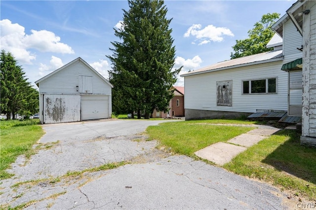 view of side of home featuring a garage, an outbuilding, metal roof, and a lawn