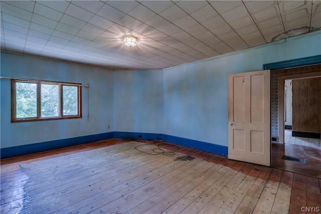 empty room featuring visible vents, light wood-type flooring, and baseboards