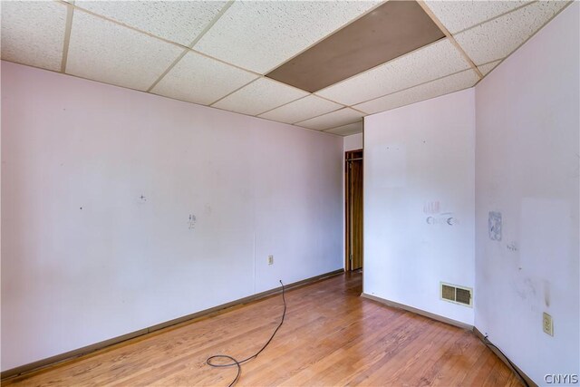 spare room with light wood-style flooring, baseboards, a drop ceiling, and visible vents