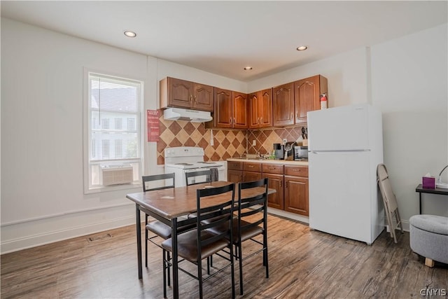 kitchen with backsplash, white appliances, and light wood-type flooring