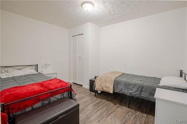 bedroom with wood-type flooring, a textured ceiling, and a closet