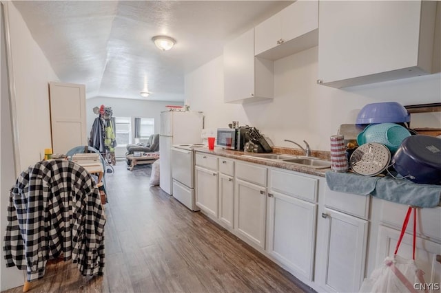 kitchen with vaulted ceiling, electric stove, sink, light hardwood / wood-style floors, and white cabinetry