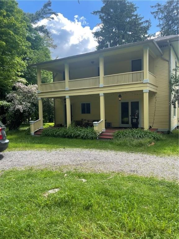 back of property featuring a balcony and a lawn