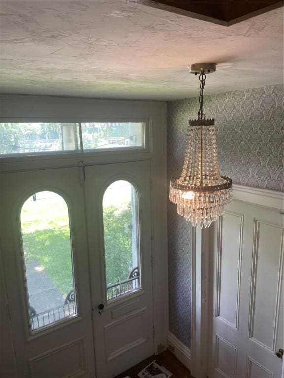 foyer entrance with a healthy amount of sunlight, wallpapered walls, and a chandelier