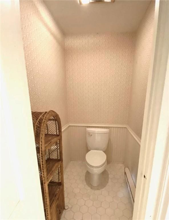 bathroom featuring a wainscoted wall, a baseboard heating unit, and toilet