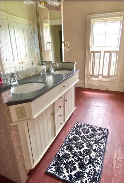 full bath with double vanity, wood finished floors, and a sink