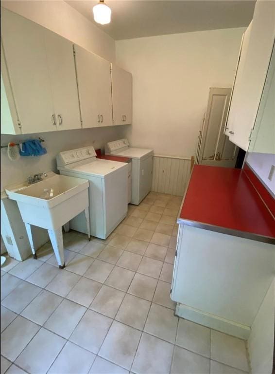 washroom with a sink, cabinet space, light tile patterned floors, and washer and dryer